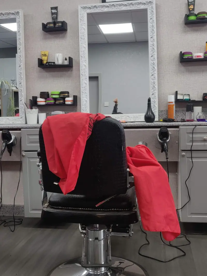 Inside the shop — barber chair, ornate white mirrors and signal-red capes
